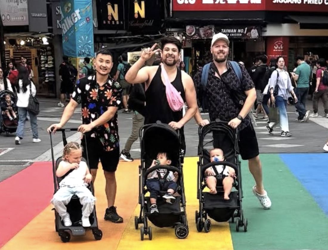 Benjamin, Ben and Mitch pushing their three kids in strollers across a rainbow crosswalk